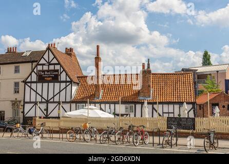 Une maison publique de style Tudor avec un toit rouge se dresse à côté d'une route à York. Un parasol se trouve dans le jardin et des vélos sont à l'avant-plan. Banque D'Images