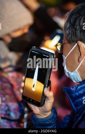 LONDRES, ANGLETERRE- 4 juin 2021: Homme tenant un smartphone avec une bougie virtuelle à un événement Remember Tienanmen 1989 à Londres Banque D'Images