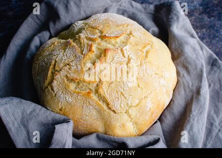 Pain de pain français enveloppé dans une serviette de table en lin : un pain de pain croûteux enveloppé dans une serviette en tissu Banque D'Images