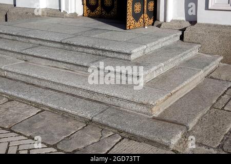 seuil en granit d'angle à l'entrée porte ouverte en fer noir rouille et façade blanche bardage en granit gris un vieux bâtiment rétro de près v Banque D'Images