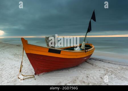 Un bateau de pêche en bois amarré près de la plage à Debki, au lever du soleil. Mer Baltique, nord de la Pologne. Banque D'Images