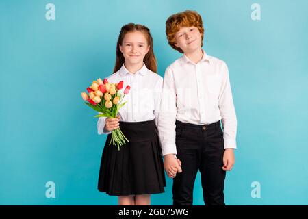 Portrait de deux enfants attrayants tenant des mains tulipes festal jour occasion isolée sur fond bleu clair de couleur. Banque D'Images