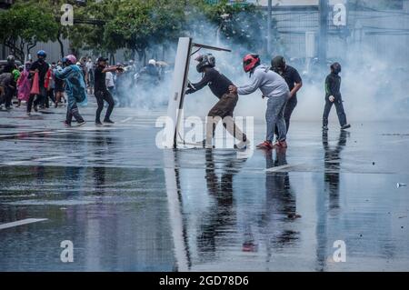 Bangkok, Thaïlande. 11 août 2021. Les manifestants utilisent une table comme bouclier lorsqu'ils s'affrontent avec des policiers thaïlandais pendant la manifestation. Des centaines de manifestants protestent contre le gouvernement au Monument de la victoire, puis ont défilé dans la région de la maison du Premier ministre pour demander sa démission. Crédit : SOPA Images Limited/Alamy Live News Banque D'Images