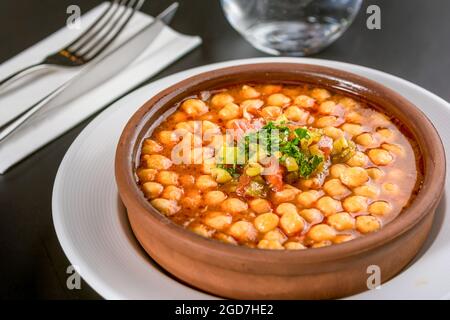 Plat traditionnel de pois chiches en cocotte sur table en pierre noire. Banque D'Images