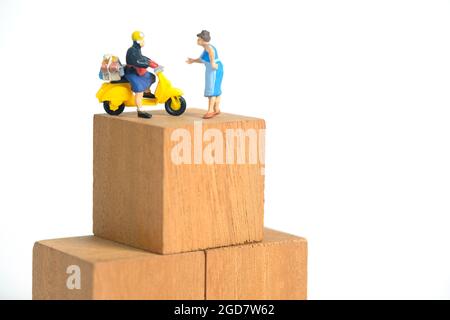 Miniature jouets personnes photographie conceptuelle. Après la livraison du colis. Courrier postal avec boîte en carton, isolé sur fond blanc Banque D'Images