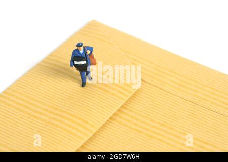 Miniature jouets personnes photographie conceptuelle. Courrier livraison par courrier postal. Courrier postal avec enveloppe, isolé sur fond blanc. Banque D'Images
