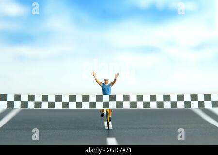 Photographie miniature de personnage de jouet de personnes. Un motard avec ligne d'arrivée, a terminé la compétition de vélo, isolé sur fond blanc. Photo d'image Banque D'Images