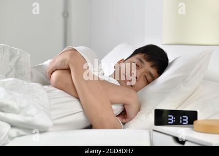 Beau jeune homme asiatique dormant au lit Banque D'Images