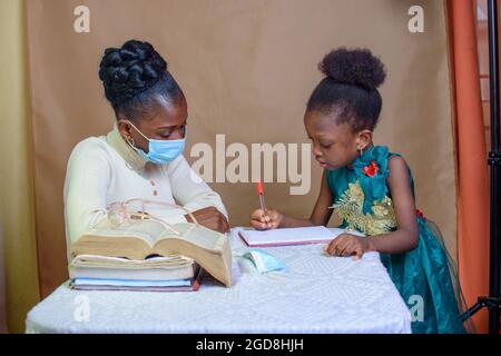 Une enseignante ou une mère africaine avec masque nasal, enseignant et aidant une petite fille avec ses études à exceller dans l'école, l'éducation et la carrière Banque D'Images