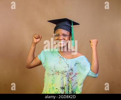 Une femme africaine nigériane ou diplômée, portant un chapeau de graduation et des lunettes, exprimant la joie due au succès de son école, de son éducation et de sa carrière Banque D'Images