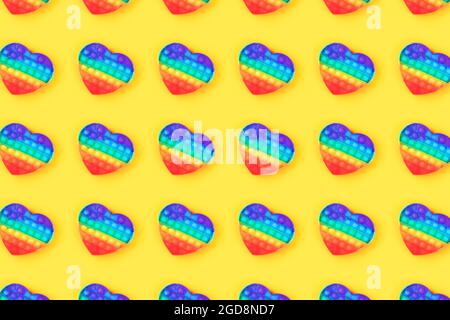 Motif fait de pop IT anti-stress jouet en forme de coeur isolé sur fond jaune. Gros plan. Banque D'Images