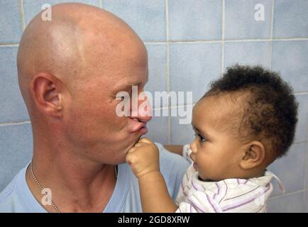 Un orphelin frotte les murmures de l'armée américaine (USA) du lieutenant-colonel (LTC) Marcus Weldon lors d'un voyage de routine dans un orphelinat catholique en Afrique au cours de l'opération ENDURING FREEDOM dans le cadre de la Force opérationnelle interarmées combinée – Corne de l'Afrique (CJTF-HOA). Les travailleurs de la mission catholique comptent beaucoup sur le personnel militaire américain pour nourrir, changer, se baigner et dissimuler les nourrissons. (PHOTO USAF PAR SSGT STACY L. PEARSALL 050826-F-7234P-156) Banque D'Images