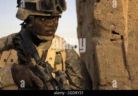 LE soldat DE l'armée AMÉRICAINE (PVT) Keith Dolvony, Charlie Wop (C TRP), 4e Bataillon (BN), 14e Cavalry (CAV), 2e peloton (PLT), assure la sécurité avec un KAC 5.56 mm Modular Weapon System (MWS) SOPMOD (opération spéciale Special modification) M4, à l'arrière d'une maison à l'extérieur de Rawah, en Irak (IRQ), Lors d'une recherche de caches d'armes pendant l'opération LIBERTÉ IRAQUIENNE. (PHOTO USAF PAR TSGT ANDY DUNAWAY 050927-F-2828D-216) Banque D'Images