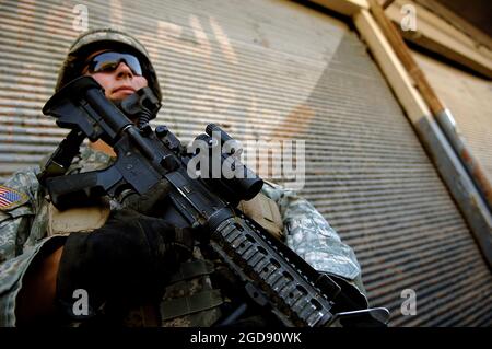 ARMÉE AMÉRICAINE (USA) Sergent (SGT) Christopher Fullbright, 1er Bataillon, 17e Régiment d'infanterie (RI) (1er/17e infanterie), TAC, 172e Brigade Stryker (BDE), fort Wainwright, Alaska (AK), Tire la sécurité dans un coin de rue lors d'une patrouille à pied à la recherche d'un véhicule impliqué dans un combat d'armes à feu avec les troupes américaines dans les rues de Mossoul, Irak (IRQ). USA SGT Fullbright est armé d'un KAC 5.56 mm système d'armes modulaires (MWS) SOPMOD (opération spéciale modification particulière) M4. USA SGT Fullbright et son unité ont été déployés pour soutenir l'opération LIBERTÉ IRAQUIENNE. (PHOTO USAF PAR TSGT JEREMY LOCK 060716-F-1644L-017) Banque D'Images