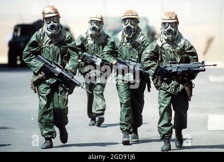 Quatre soldats de la 82e Division aéroportée se promèneront dans leur camp en portant des combinaisons de pluie, des gants et des masques de protection M-17A1 pendant qu'ils tentent d'acclimater leur corps à la chaleur de l'été saoudien pendant l'opération Desert Shield. (PHOTO USAF PAR SSGT F. LEE CORKRAN DF-ST-91-06499) Banque D'Images