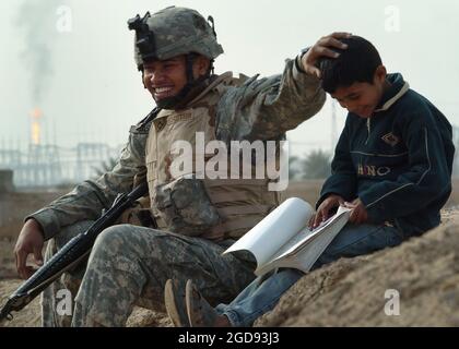 DEREK Castro, spécialiste DE l'armée AMÉRICAINE (États-Unis), affecté au 1-66e Bataillon, 1re Brigade, 4e Division d'infanterie, s'entretient avec Ali, un garçon iraquien de 10 ans, lors d'une visite de bonne volonté dans la ville d'Istaqal, en Irak, au cours de l'opération LIBERTÉ IRAKIENNE. (PHOTO US NAVY PAR PH1(AW) MICHAEL LARSON 060212-N-6901L-353) Banque D'Images