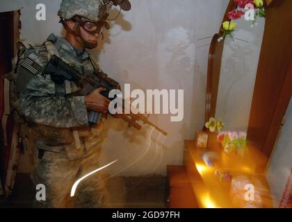 Un soldat de l'armée américaine (États-Unis) du 7e Escadron (SQN), du 10e Régiment de cavalerie (CAV REGT), de la 1re Brigade combat Team (BCT), de la 4e Division d'infanterie (ID), de fort Hood (Texas), cherche une résidence à Nubai, en Irak, au cours d'une mission d'assaut aérienne pour rechercher des insurgés et des caches d'armes durant l'opération LIBERTÉ IRAKIENNE. Le soldat est armé d'un système d'armes modulaires (MWS) KAC 5.56 mm SOPMOD (opération spéciale modification particulière) M4. (PHOTO US NAVY PAR MC1(AW) MICHAEL LARSON 060703-N-6901L-069) Banque D'Images