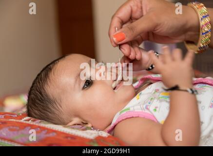 portrait d'une adorable petite fille indienne qui mange du porridge avec une cuillère. Banque D'Images