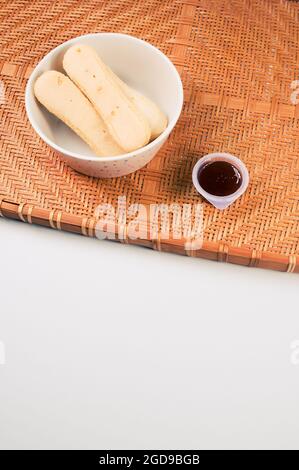 Petits gâteaux avec ketchup trempés sur un plateau en osier en bambou isolé sur fond gris Banque D'Images