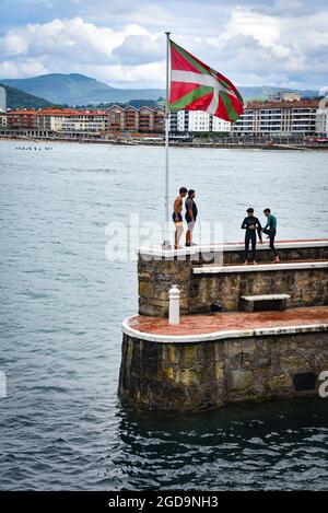 Zarautz, Espagne - 25 juillet 2021 : les adolescents de la région sautent dans la mer depuis les murs du port de la ville de Zarautz, dans le pays Basque Banque D'Images