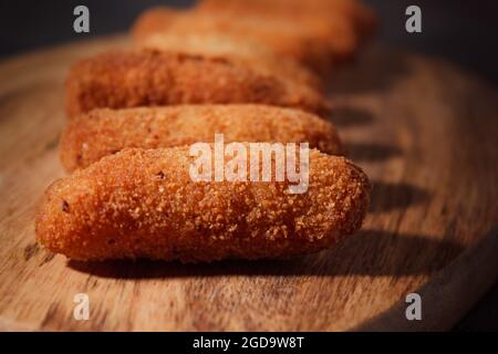 Croquettes espagnoles traditionnelles faites maison sur bois et fond noir. Tapas. Nourriture sombre. Banque D'Images