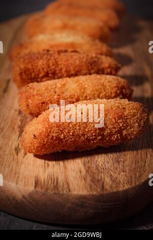 Croquettes espagnoles traditionnelles faites maison sur bois et fond noir. Tapas. Nourriture sombre. Banque D'Images