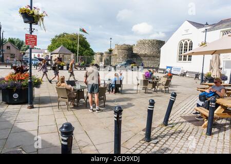 Les gens qui profitent du soleil sur la place du Château à Beaumaris Anglesey avec l'ancienne cour et le château de Beaumaris en arrière-plan Banque D'Images