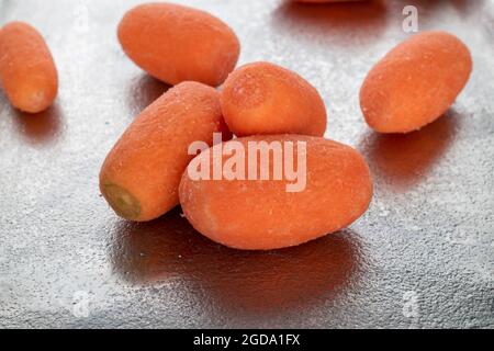 Plusieurs mini carottes mûres et biologiques sur un plateau en métal, gros plan. Banque D'Images