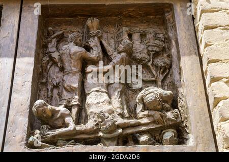 Extérieur de l'église médiévale San Pietro à Cassano Spinola, dans la province d'Alessandria, Piémont, Italie. Porte. Jésus Christ et croix à l'envers Banque D'Images