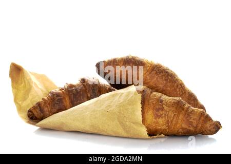 Trois croissants maison parfumés, enveloppés de papier, isolés sur du blanc. Banque D'Images