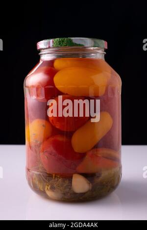 légumes en conserve dans un pot sur une table blanche et un fond noir Banque D'Images