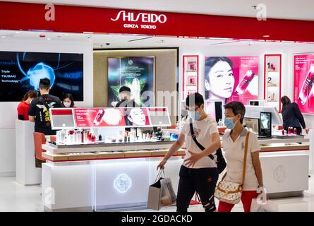 Les amateurs de shopping portant des masques faciaux se promène devant la société multinationale japonaise de soins personnels Shiseido, qui se trouve à Hong Kong. Banque D'Images