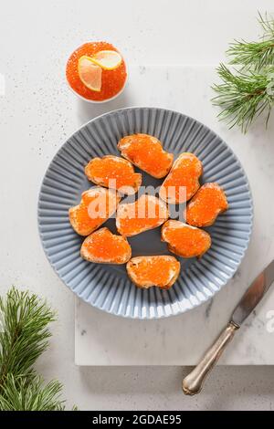 Canapés russes avec caviar rouge sur ciabatta sur fond de marbre blanc pour Noël, fête du nouvel an. Vue de dessus. Banque D'Images