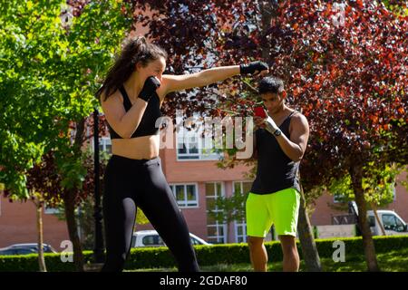 Jeune athlète de boxe avec son entraîneur personnel dans le parc lors d'une préparation à une compétition Banque D'Images