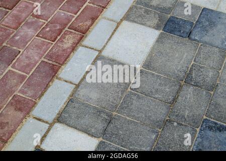 Dalles ou pierres en béton ou pavés gris et rouge récemment posés pour les sols ou les allées. Pavés de béton dans l'arrière-cour ou pavés routiers. Jardin Banque D'Images