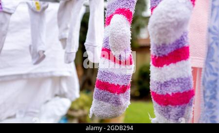 Lavage sur une ligne de lavage avec une vieille paire de chaussettes dénudées au premier plan. Banque D'Images