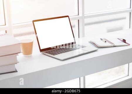 Ordinateur portable écran vierge sur blanc propre table de travail confortable bureau espace de travail dans le café. Banque D'Images