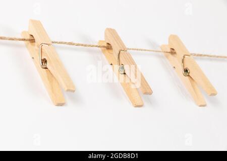 trois épingles à linge en bois avec ressort en métal accrochent sur une corde sur fond blanc. mise au point sélective Banque D'Images