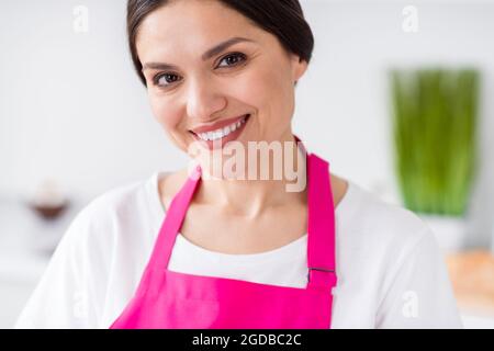 Photo rognée de cheveux brunette optimiste femme millénaire porter un tablier de t-shirt blanc à la cuisine Banque D'Images