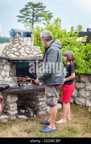 Soirée barbecue. Le père et le fils cuisent de la viande sur un barbecue à la fête du barbecue dans l'arrière-cour. Concept de nourriture, de personnes et de temps en famille Banque D'Images