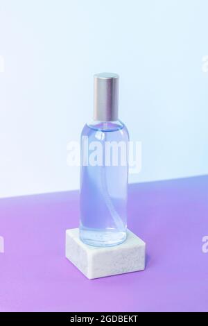 Eau de lavande ou hydrolat en bouteille de verre sur podium gris sur table pourpre. Concept d'aromathérapie. Maquette. Banque D'Images