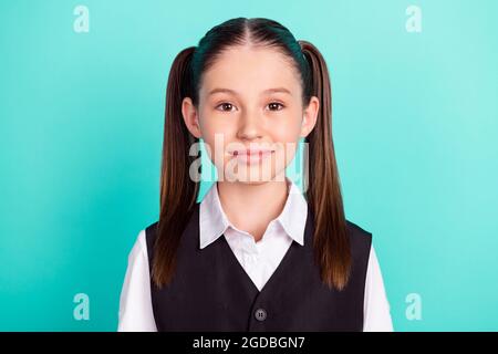 Photo portrait petite fille avec queues souriant dans un décor uniforme et isolé couleur teal pastel Banque D'Images