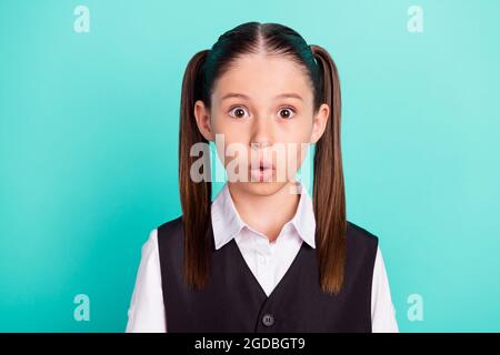 Photo portrait petite fille avec queues portant uniforme scolaire excitée étonnant isolé teal couleur d'arrière-plan Banque D'Images