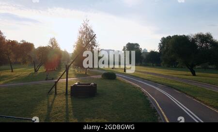 Une piste cyclable sinueuse dans le parc. Il serpente à travers les arbres et les buissons. Filmé à l'aube, au lever du soleil. Photographie aérienne. Banque D'Images