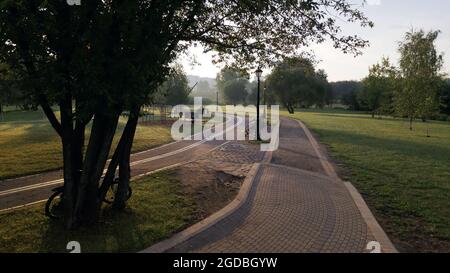 Une piste cyclable sinueuse dans le parc. Il serpente à travers les arbres et les buissons. Filmé à l'aube, au lever du soleil. Photographie aérienne. Banque D'Images