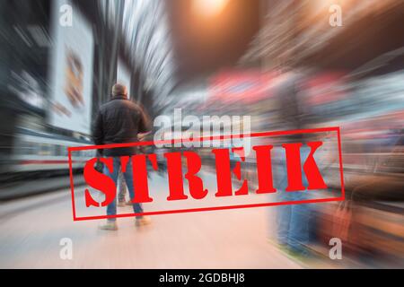 Homme en attente du train sur une plate-forme dans la gare de la grande ville et bannière avec le texte allemand Streik (signifiant grève), bruit de fond de foule flou Banque D'Images