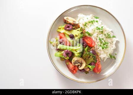 Repas végétarien à base de brocoli, tomates et olives avec riz sur une assiette grise, cuisson avec des légumes sains, fond clair avec espace de copie, haut Banque D'Images