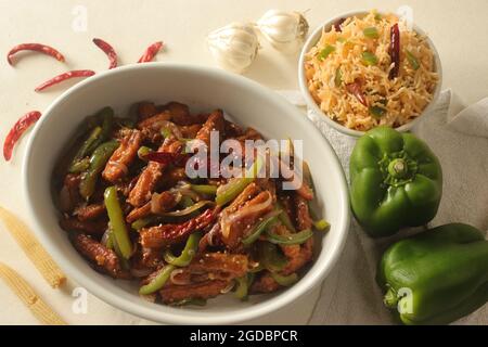 Bébé maïs manchurien. Maïs frit croustillant dans une sauce manchurienne avec poivrons et oignons. Servi avec du riz frit. Prise de vue sur bac blanc Banque D'Images