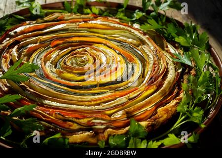 Tarte aux légumes soleil mexicain. Tarte ouverte ronde à base de courgettes, d'aubergines et de carottes. Vue rapprochée du dessus. Aliments sains à base de légumes. Végétarisme. Spirale Banque D'Images