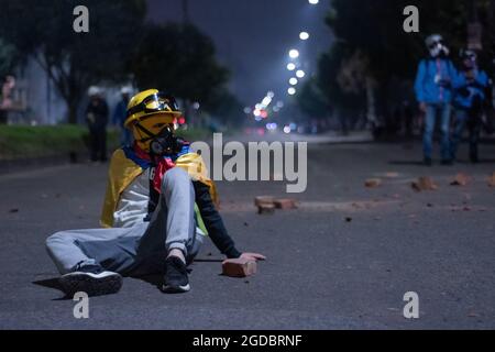 Bogota, Colombie. 11 août 2021. Un manifestant de première ligne utilise le drapeau colombien alors que des affrontements se sont produits entre les manifestants et la police anti-émeute de Colombie (ESMAD) dans le nord de Bogota, en Colombie, pour admirer l'expulsion et la déforestation d'une réserve naturelle le 11 août 2021. Crédit : long Visual Press/Alamy Live News Banque D'Images